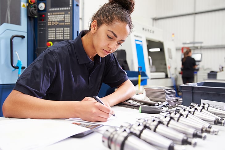 Young woman working on manufacturing product design in front of a CNC machine